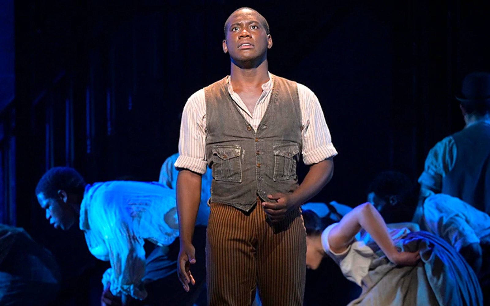 Performer on stage during Paradise Square musical scene.