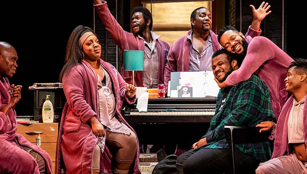 Cast members of "A Strange Loop" performing on stage in a lively scene.