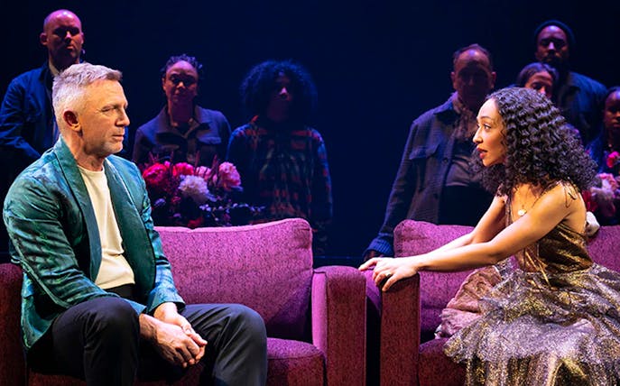 Actors performing a scene from Macbeth on stage with a seated audience in the background.