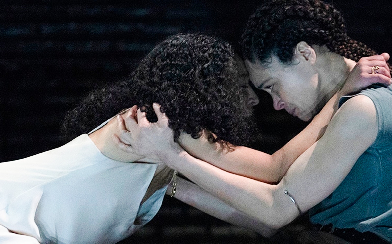 Two actors in an intense scene from Macbeth, embracing on stage.