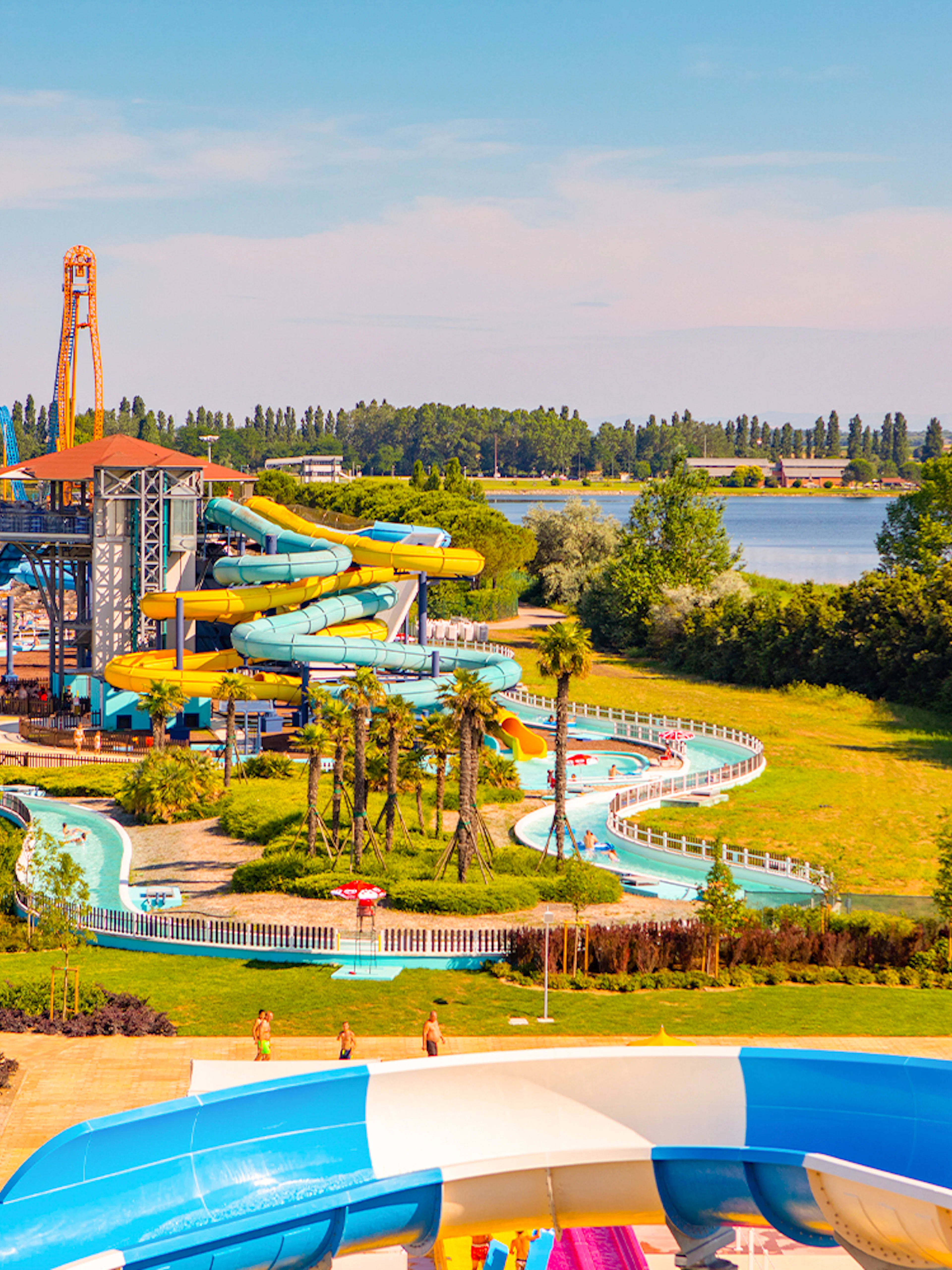 Water park with colorful slides and lazy river at Mirabeach, surrounded by greenery and a lake.