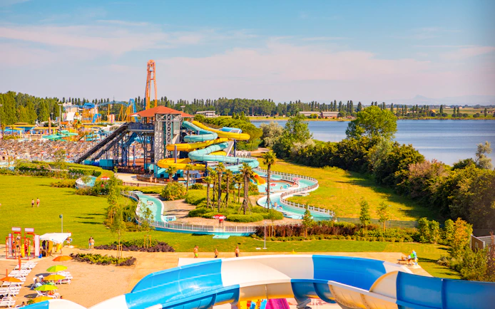 Water park with colorful slides and lazy river at Mirabeach, surrounded by greenery and a lake.