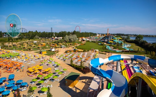 Water park at Mirabeach with colorful slides, sun loungers, and a Ferris wheel in the background.