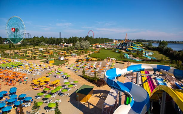 Water park at Mirabeach with colorful slides, sun loungers, and a Ferris wheel in the background.