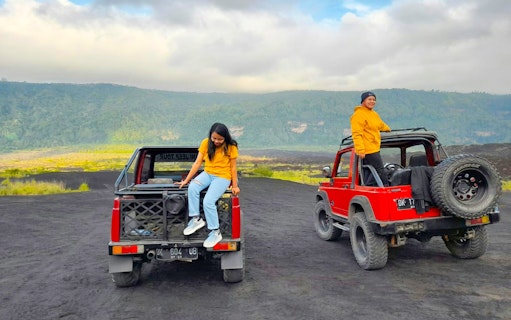 Two people on red jeeps during Bali Mount Batur sunrise tour.