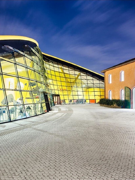 Museo Enzo Ferrari Modena entrance with modern glass facade and historic building.