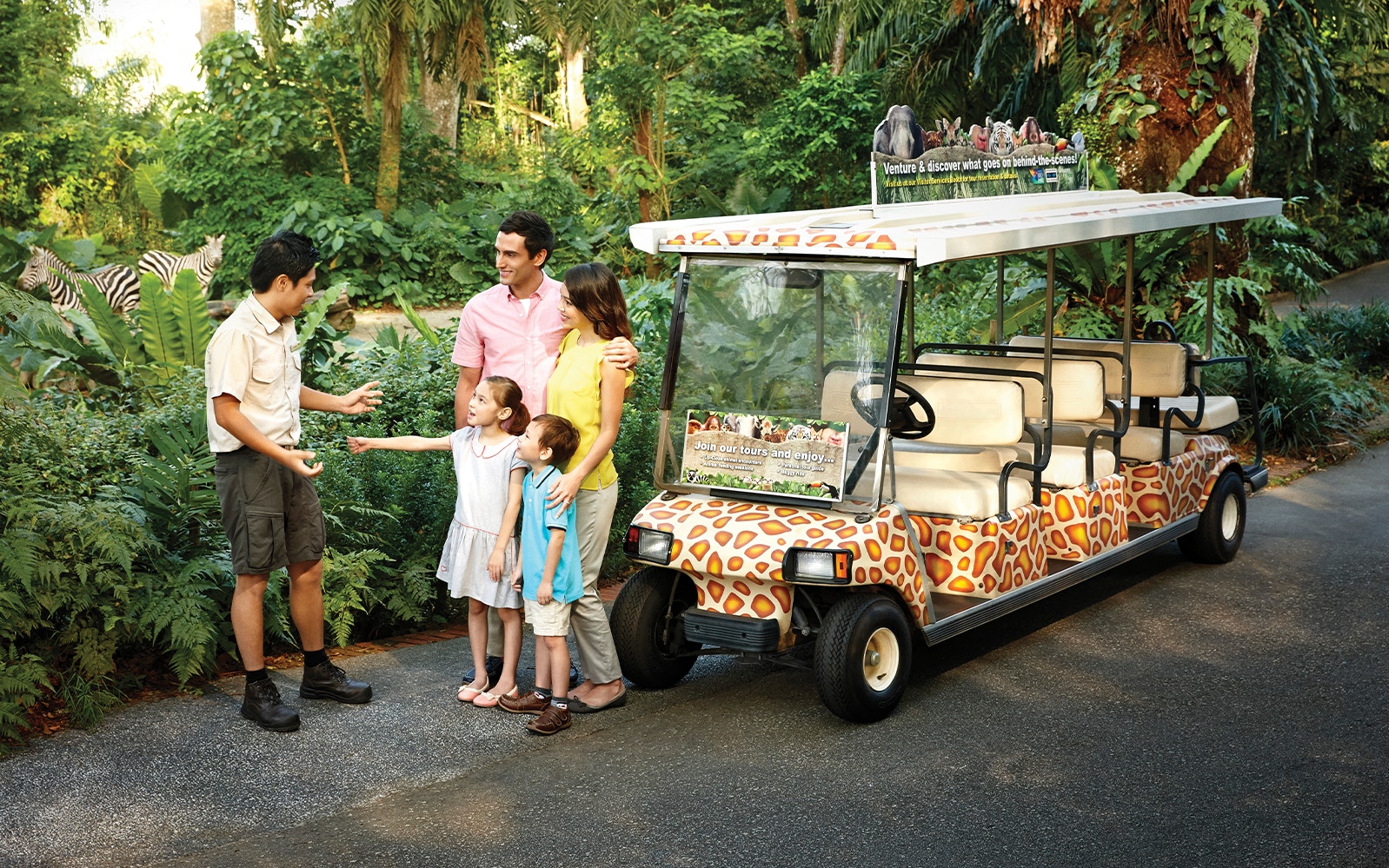 Family with guide near safari tram at Singapore Zoo.