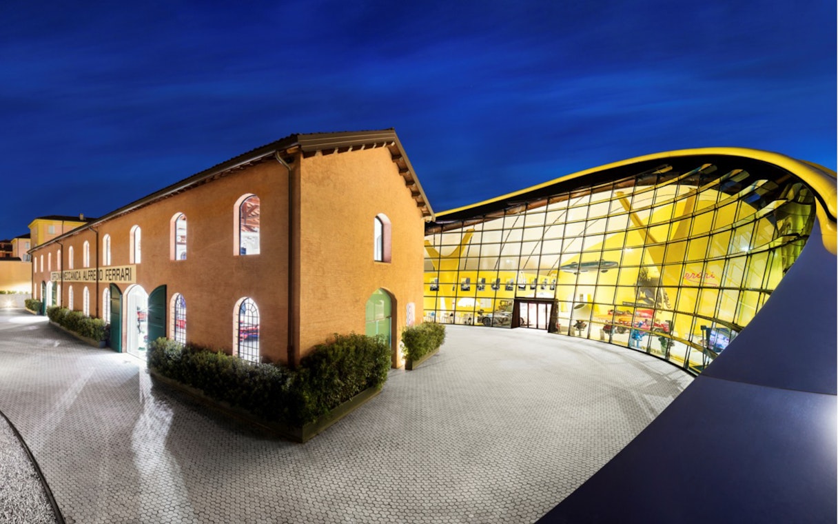 Maranello Ferrari Museum and Modena Enzo Ferrari Museum exterior at night.