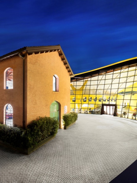 Maranello Ferrari Museum and Modena Enzo Ferrari Museum exterior at night.