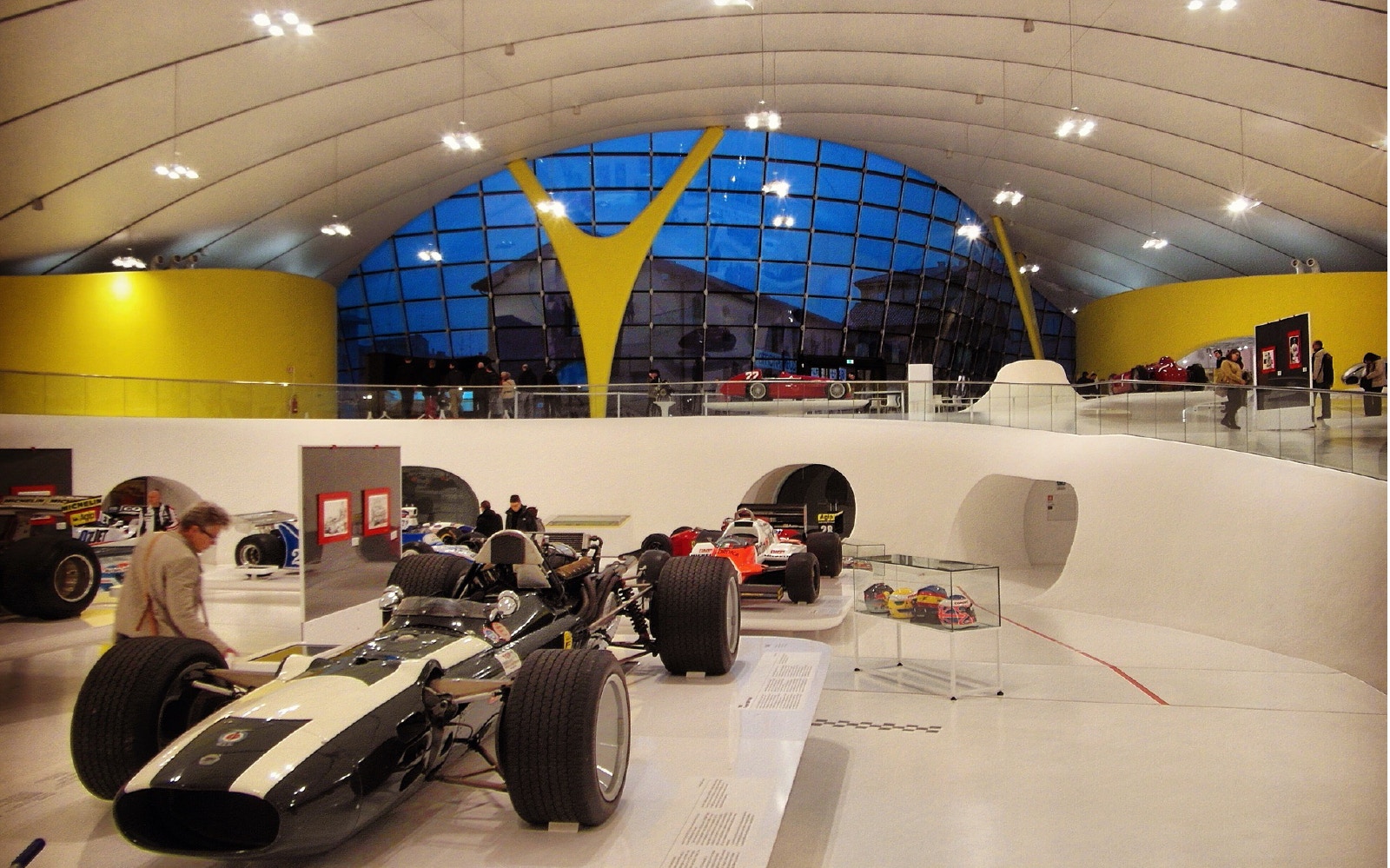 Ferrari race cars displayed at Modena Enzo Ferrari Museum with visitors exploring exhibits.