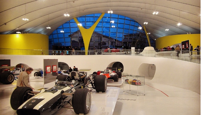 Ferrari race cars displayed at Modena Enzo Ferrari Museum with visitors exploring exhibits.