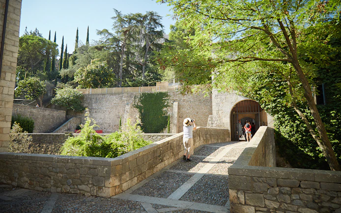 Visitor exploring historic stone walls in Girona, Spain.