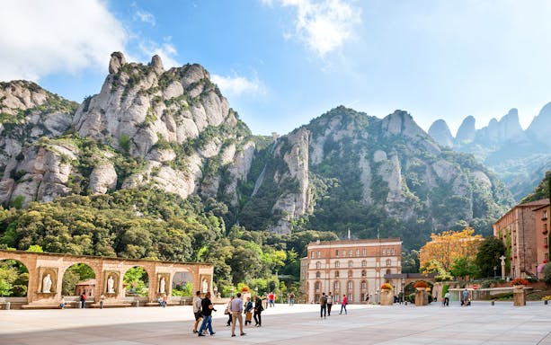 Montserrat mountain view with tourists in courtyard, Catalonia, Spain.