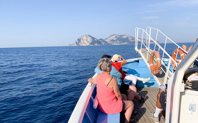 Tourists on a boat approaching Capri Island during a guided tour with Sorrento transfers.