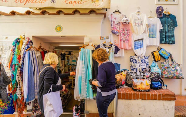 Tourists shopping for souvenirs at a local store on Capri Island during a guided tour.