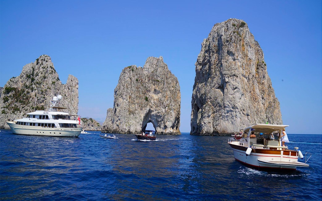 Boats near Faraglioni rock formations on Capri Island during guided tour.