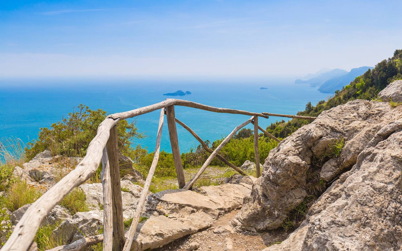 Path of the Gods trail overlooking the sea with rocky landscape and wooden railing.