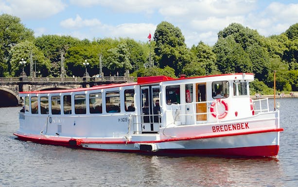 Tour boat on Alster Lake in Hamburg, Germany, near a historic bridge.