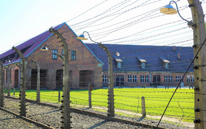 Auschwitz-Birkenau Museum building behind barbed wire fence.