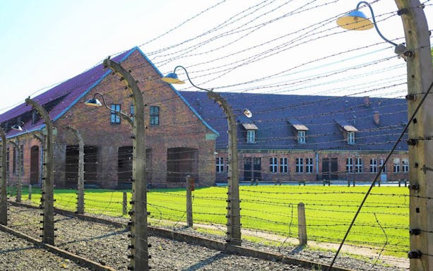 Auschwitz-Birkenau Museum building behind barbed wire fence.
