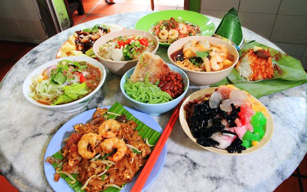 Local dishes on a table in Penang Georgetown, featuring noodles, rice, and desserts from the food trail.