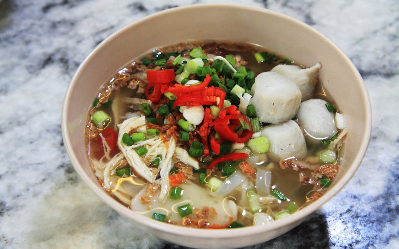 Bowl of Penang noodle soup with fish balls and vegetables on Georgetown food trail.