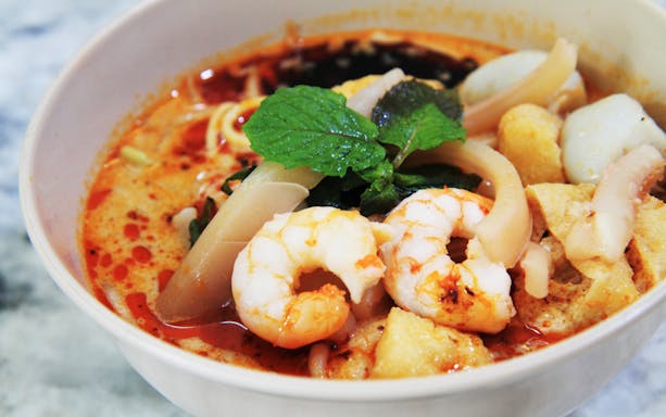 Bowl of Penang laksa with prawns and herbs, part of Georgetown food trail.