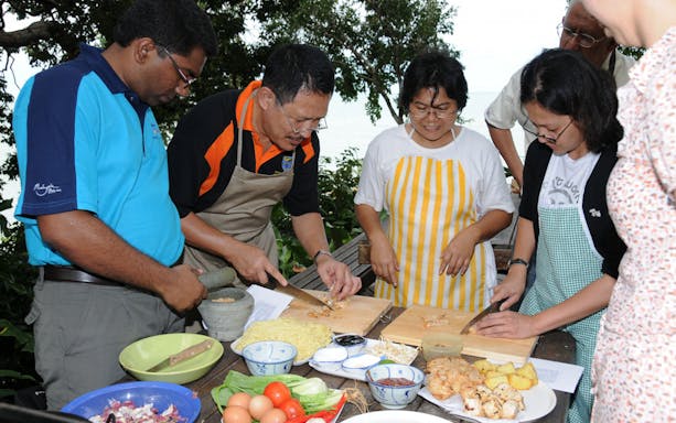 Group cooking class in Penang preparing local dishes with fresh ingredients.