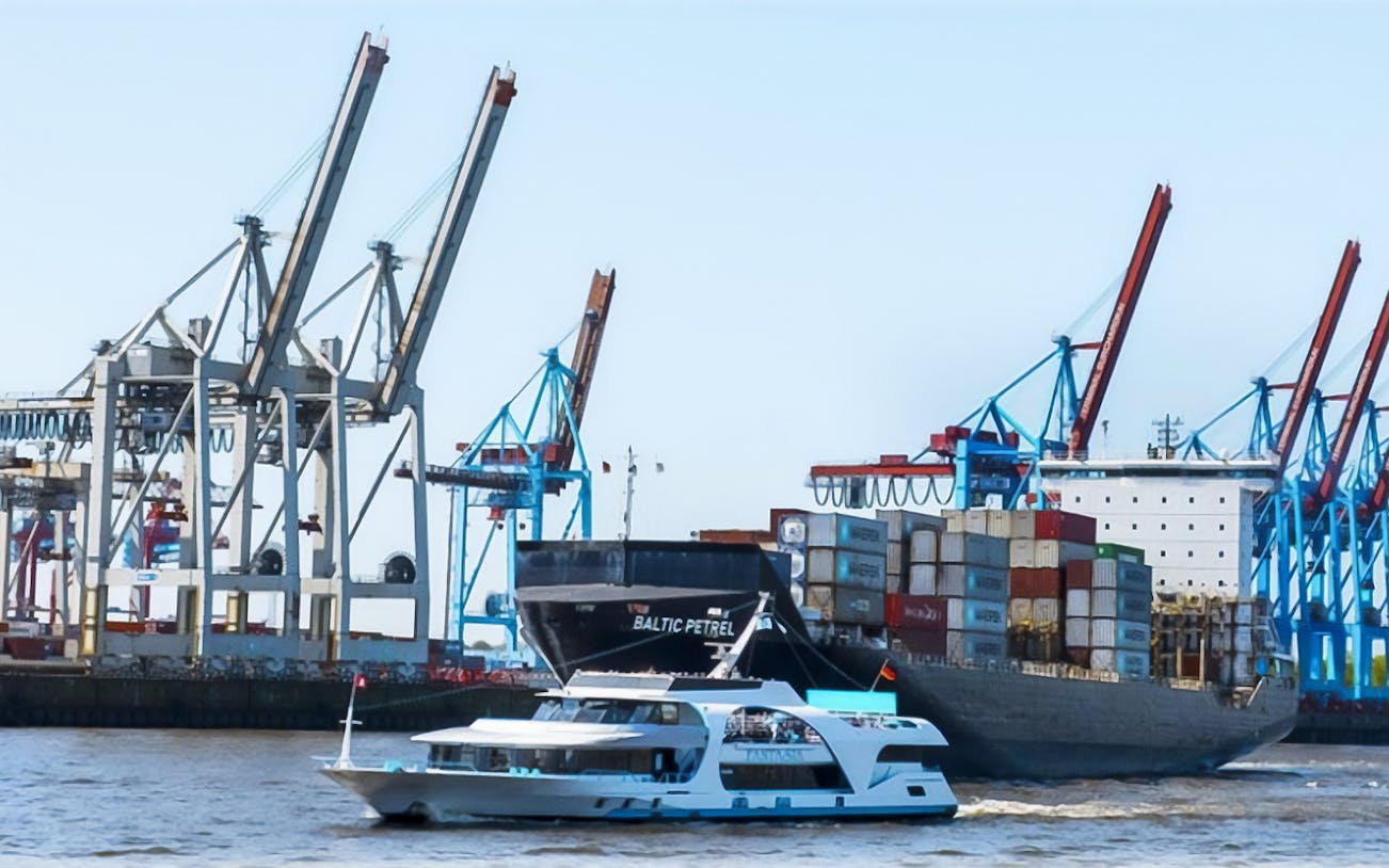 Tour boat passing container ship and cranes in Blankenese harbor, Hamburg.