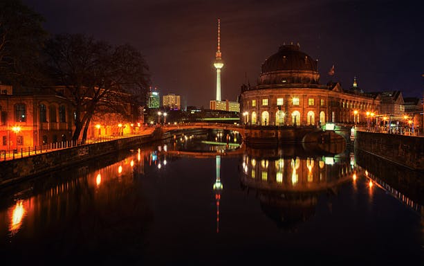Berlin cityscape at night with TV Tower and Bode Museum reflecting in the Spree River.