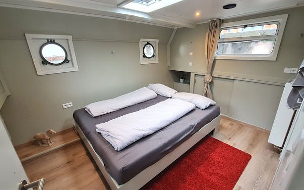 Cozy cabin interior on a Spree river cruise, featuring a double bed and porthole windows.