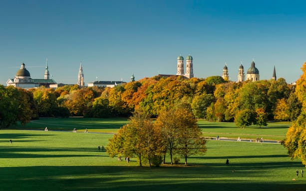 Munich skyline and English Garden with people walking and cycling.