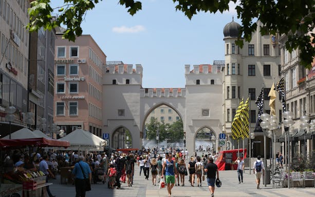 Crowd walking through Karlstor gate in Munich on a sunny day.