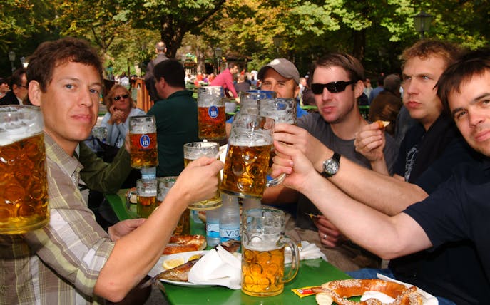 Group enjoying beer at an outdoor brewery tour with pretzels on the table.