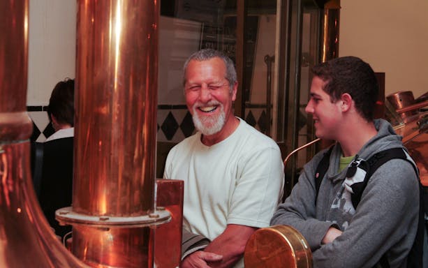 Visitors enjoying a brewery tour with copper brewing equipment.