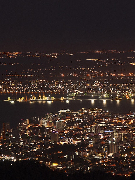 Night view of Penang cityscape from Penang Hill, Malaysia, with illuminated buildings and coastline.