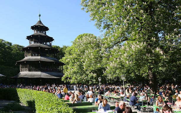 People enjoying a sunny day at the Chinese Tower beer garden in Munich's English Garden.