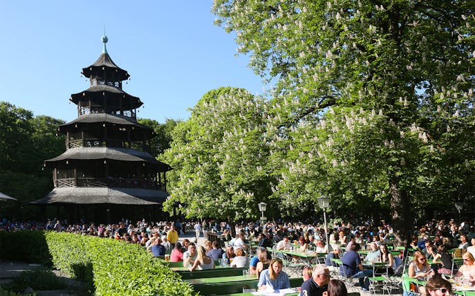 People enjoying a sunny day at the Chinese Tower beer garden in Munich's English Garden.