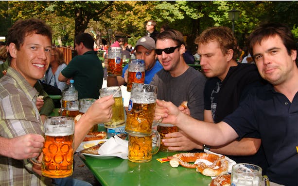 Group enjoying beer and pretzels at a beer garden in the English Garden, Munich.