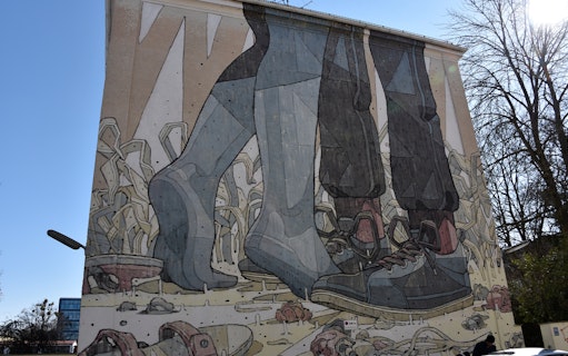 Street art mural depicting large feet in shoes on a building in Munich.