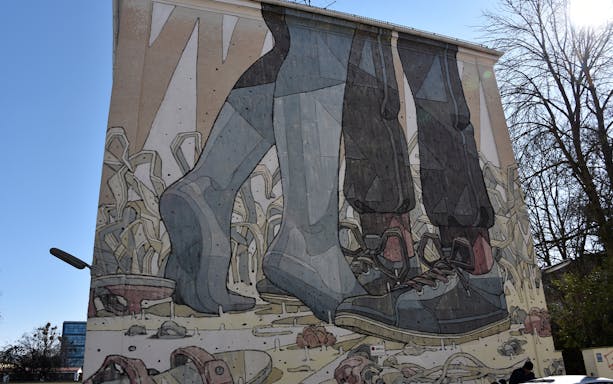 Street art mural depicting large feet in shoes on a building in Munich.