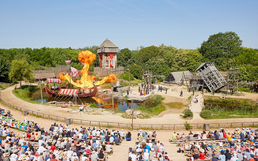 Viking ship battle reenactment with fire effects at Puy du Fou Theme Park, France.