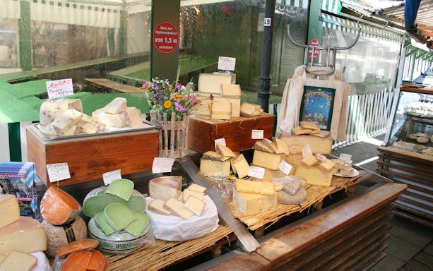 Cheese selection at a Bavarian market stall with various types and labels.
