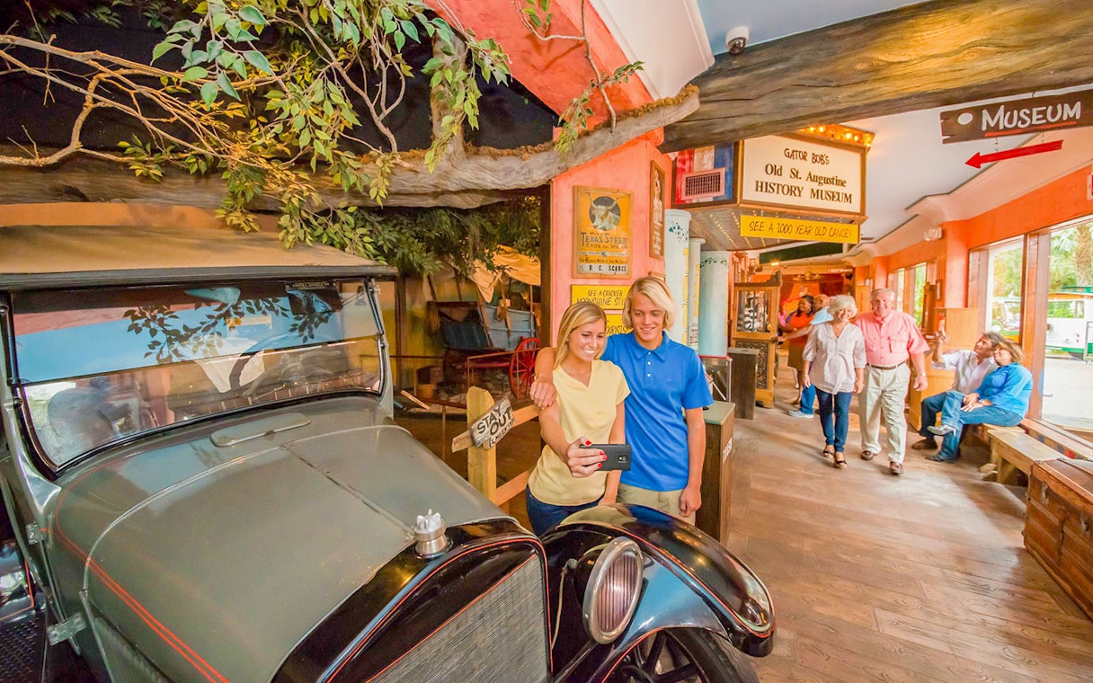 Visitors taking a selfie near a vintage car at St. Augustine History Museum.