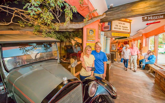 Visitors taking a selfie near a vintage car at St. Augustine History Museum.
