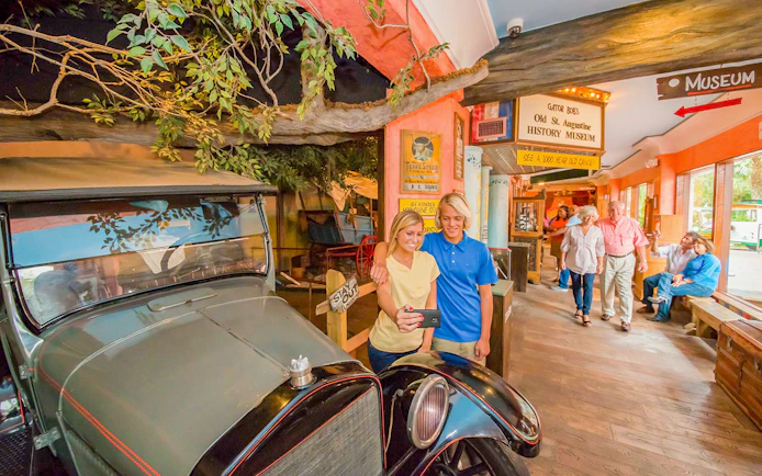 Visitors taking a selfie near a vintage car at St. Augustine History Museum.