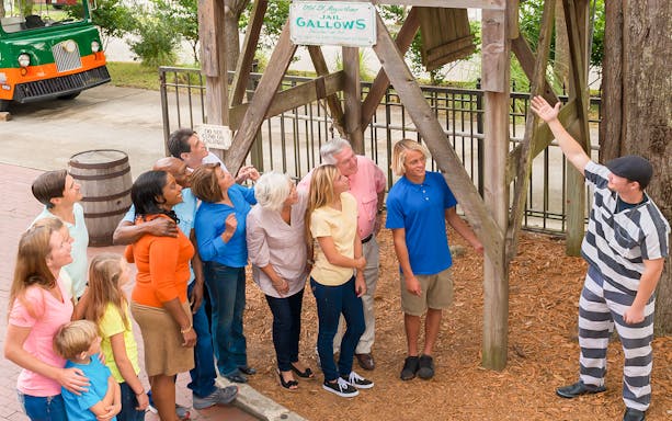 Tour group at St. Augustine Old Jail Museum gallows with guide in striped uniform.