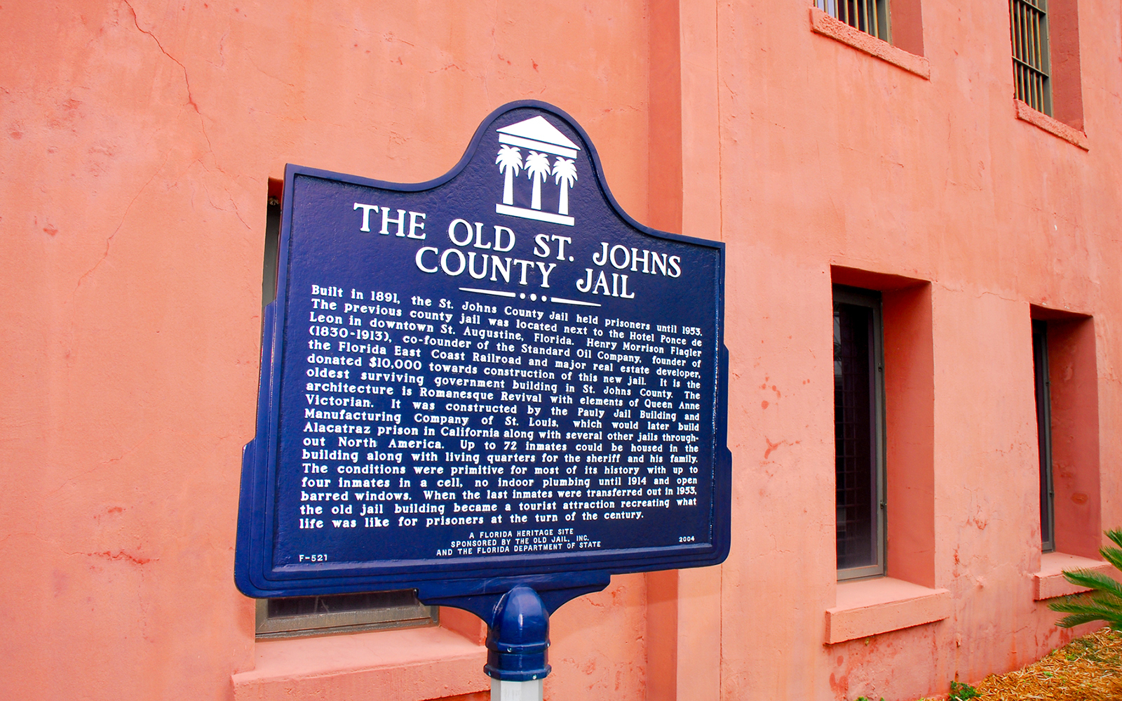 St. Augustine Old Jail Museum sign with historical details on a pink wall.