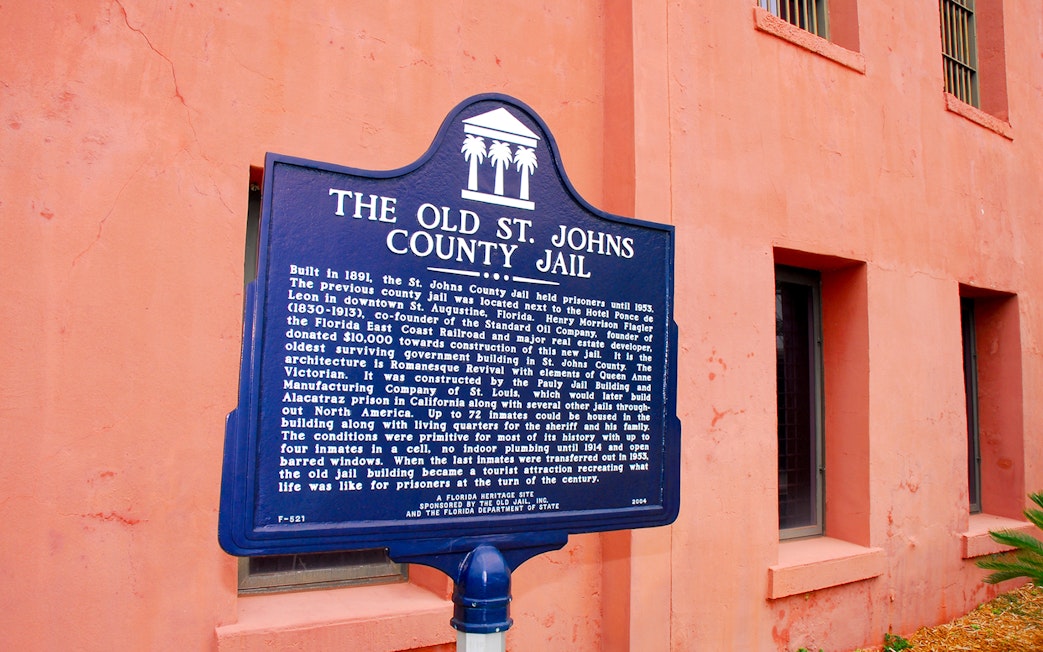 St. Augustine Old Jail Museum sign with historical details on a pink wall.