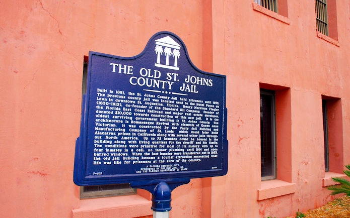 St. Augustine Old Jail Museum sign with historical details on a pink wall.